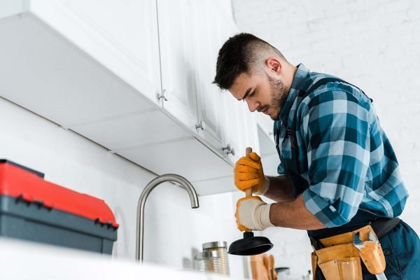 selective-focus-of-repairman-holding-plunger-in-ki-resize.jpg